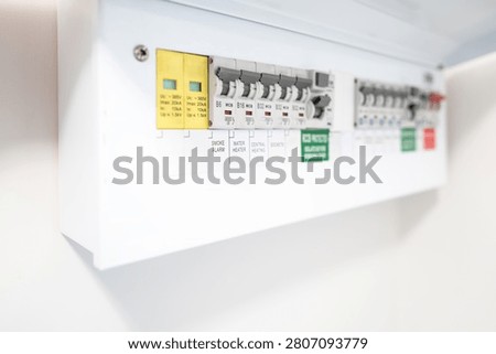 Close-up of a newly installed electrical distribution and safety panel showing individual circuit breakers and the red coloured mains electric cut off switch. Seen in a newly renovated apartment.