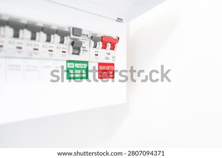 Close-up of a newly installed electrical distribution and safety panel showing individual circuit breakers and the red coloured mains electric cut off switch. Seen in a newly renovated apartment.