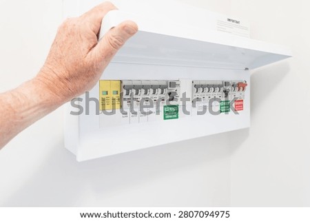Close-up of a newly installed electrical distribution and safety panel showing individual circuit breakers and the red coloured mains electric cut off switch. Seen in a newly renovated apartment.
