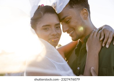 Closeup of newlywed biracial couple romancing under veil at beach against clear sky at sunset. Copy space, unaltered, love, together, destination wedding, beach, event, tradition, celebration, happy. - Powered by Shutterstock