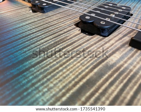 Closeup nickel stings and black pickup the blue burst  modern electric guitar satin finish patterned wood flame maple grain with copy space for text. music business concept.