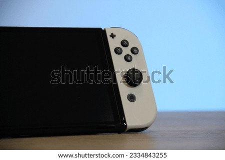 A closeup of a Nintendo Switch OLED Gaming Handheld on a wooden table