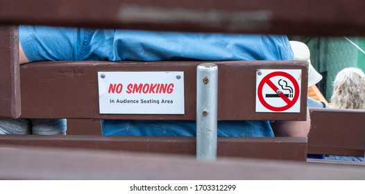 Closeup Of A NO SMOKING Sign On The Back Of A Wooden Bench At An Outdoor Concert Venue.