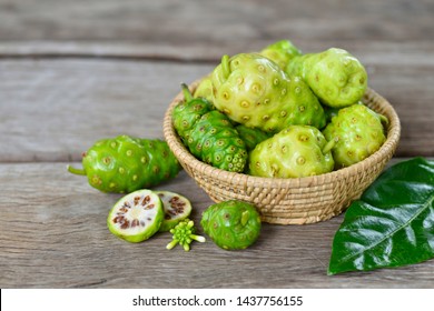 Close-up Noni or Morinda Citrifolia fruits sliced with bamboo basket on old wood.