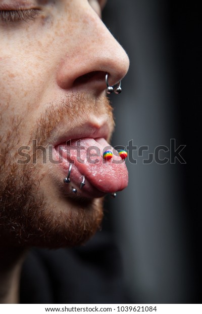 Closeup of nose (septum) and tongue piercings of\
young man