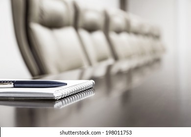 Closeup of notepad for agenda kept on table in empty corporate conference room before business meeting