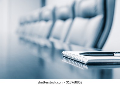 Closeup of notepad for agenda kept on table in empty corporate conference room before business meeting in blue tone - Shutterstock ID 318968852