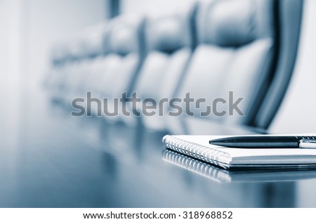 Closeup of notepad for agenda kept on table in empty corporate conference room before business meeting in blue tone