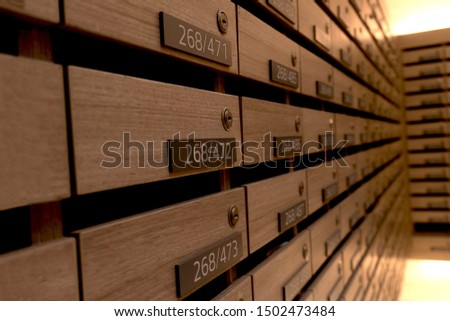 Closeup of numbered mailboxes and lockers in raw in the condo. Natural wooden letterbox panel pattern .