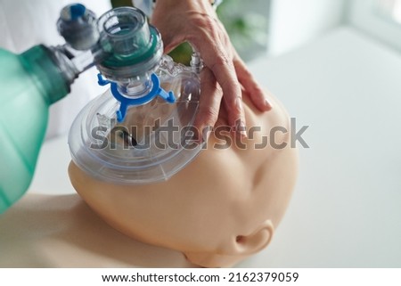 Close-up of nurse putting oxygen mask on face of mannequin and learning to use it during training