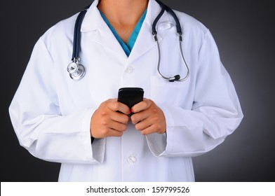 Closeup Of A Nurse Texting On Her Cell Phone. The Medical Professional Is Unrecognizable Showing Torso Only. Horizontal Format On A Light To Dark Gray Background.