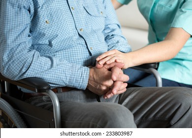 Close-up of nurse touching hand her handicapped patient