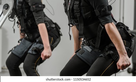 Closeup O Two Women Squatting During EMS Workout At Gym