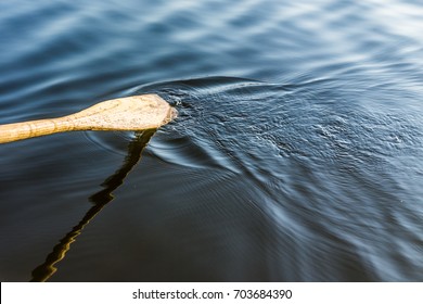 Closeup of oar paddle from row boat moving in water on green lake with ripples - Shutterstock ID 703684390