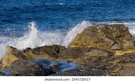 Close-up of ocean waves crashing on rugged coastal rocks; vibrant blue water and white spray capture natural energy and seaside tranquility in a dynamic, scenic coastline - Powered by Shutterstock