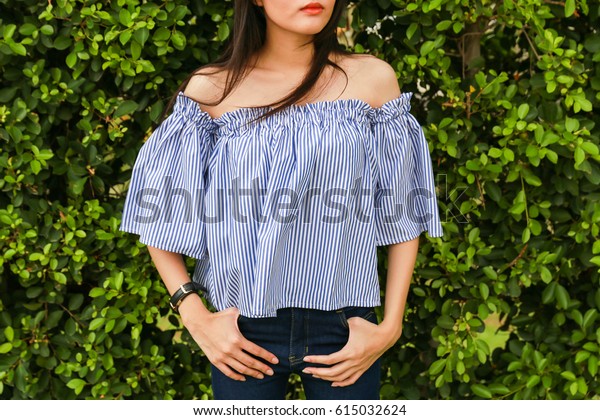 Close-up Off the Shoulder blue shirt and blue\
jeans on trees\
background
