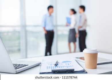 Close-up of office desk with business team behind