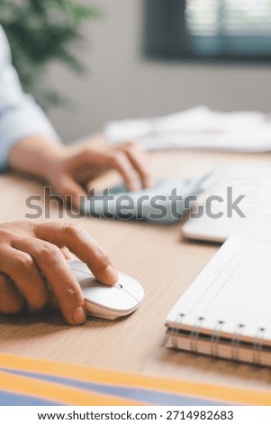 Close-up of office worker using computer mouse while working at desk, illustrating digital tasks, productivity, online work, business workflow and modern workplace technology.