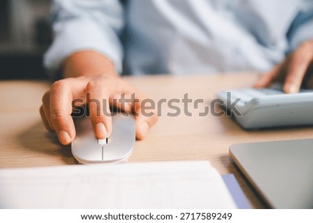 Close-up of office worker using computer mouse while working at desk, illustrating digital tasks, productivity, online work, business workflow and modern workplace technology.