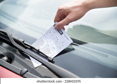 Close-up of officer's hand putting parking ticket on car windshield