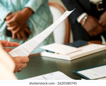 Close-up of an official document held and read by a civil registrar during a wedding ceremony at the town hall.