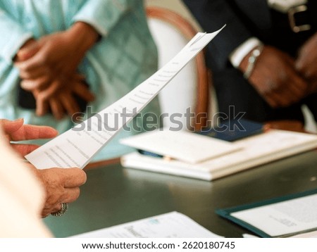Close-up of an official document held and read by a civil registrar during a wedding ceremony at the town hall.