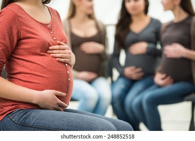 Close-up ofl pregnant woman's belly. Happy pregnant women are talking together at antenatal class at the hospital on background. - Powered by Shutterstock