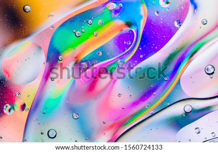 Closeup of oil drops motion on water surface.  Colorful abstract macro background of oil drops on water surface with air bubbles inside