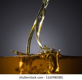 Close-up of oil and liquid pouring  with splashing on dark background. Isolated studio shooting