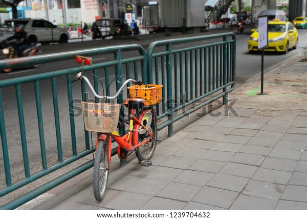 closeup of old bicycle parking on pavement and locked to\
street barrier 