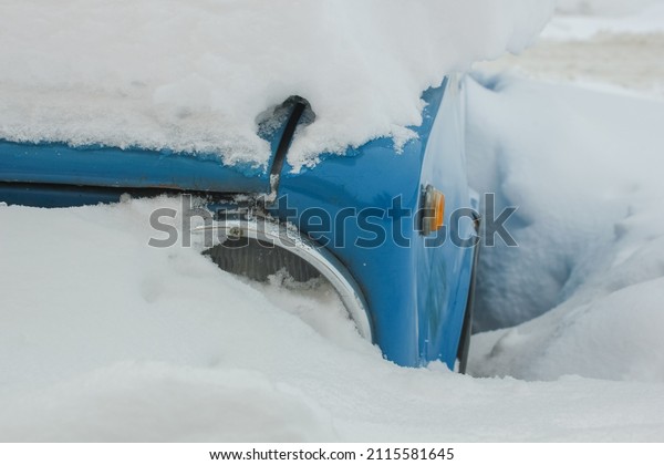 close-up of Old blue\
car\'s headlight under a snowdrift. Heavily snow-covered retro car\
buried in the city\
street.