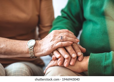 Closeup Of An Old Caucasian Man And An Old Caucasian Woman Sitting In A Couch Holding Hands With Affection. Elderly Couple Holding Hands. Senior Married Couple's Hands