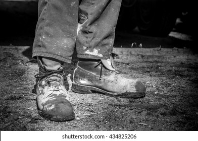 closeup of old and dirty cement worker boots in black and white