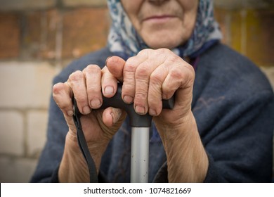 Close-up Of Old Dirty Wrinkled Woman Hands Holding Walking Stick. Senior People Health Care