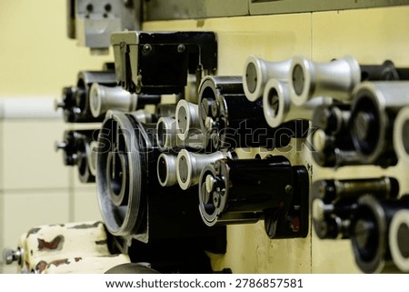 A close-up of an old film developing machine’s control panel and drive system, showing aged mechanical components and worn textures.