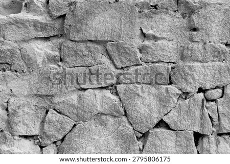 Close-up of old gritty stone structure in greyscale.