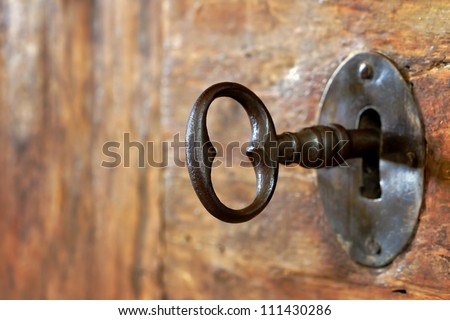 Closeup of an old keyhole with key on a wooden antique door