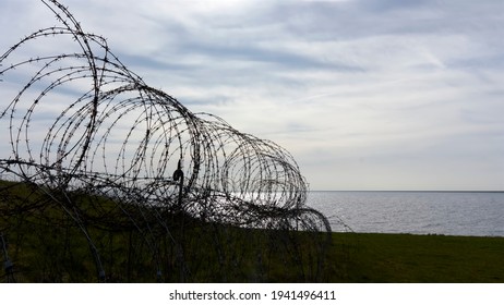 Closeup of old metal barbed wire from the second world war. Sharp razor wire fence near the sea during sunset.  Concept of prison, immigration, detention, boundary, defence or war. - Powered by Shutterstock