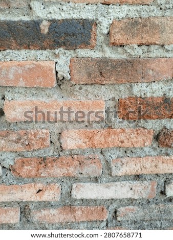 Close-up of an old red brick wall with rough cement mortar, showcasing natural weathering, detailed texture, and rustic construction materials. Ideal as a background for architecture, renovation, and vintage design concepts.
