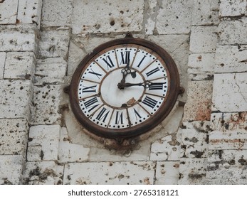 Close-up of an old, rusty clock on an ancient stone wall, historical context.