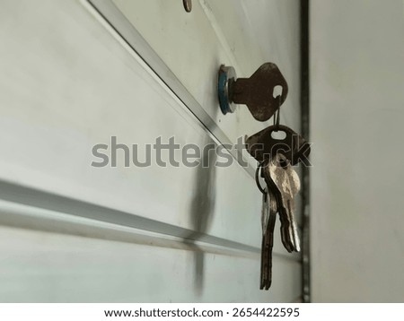 Close-up of old rusty keys hanging from a lock on a metal garage door