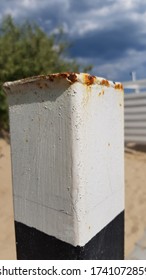 Closeup Of Old Rusty Metal Pillar Painted In White And Black Colors. White Painted Metallic Surface With Rusty Drips And Stains