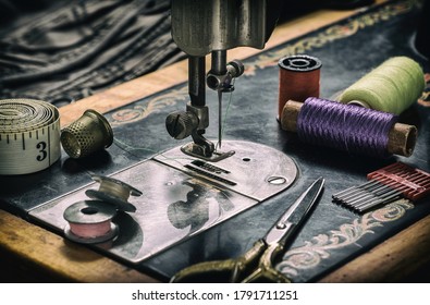 Closeup of an old sewing machine and accessories for sewing, scissors, needles and a tailor tape on a table. The concept of sewing accessories. Retro toning