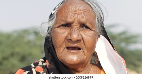 A Closeup Of An Old South Asian Woman With A Coronavirus Face Mask Hanging Down From Her Ear