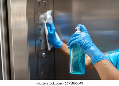 Closeup of old staff hand using wet wipe cleaning an elevator push button control panel with a blue sanitizer bottle.Disinfection,cleanliness and healthcare,Anti Corona virus,COVID-19.Selective focus. - Shutterstock ID 1691866843