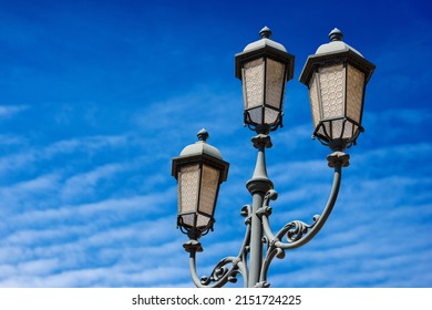 Close-up of old street lamp posts against a clear blue sky with clouds and copy space. Loggia town square (Piazza della Loggia), Brescia downtown, Lombardy, Italy, Southern Europe.