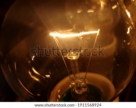 Closeup of old tungsten bulb glowing in the dark - energy inefficient light that is now replaced with LED illumination