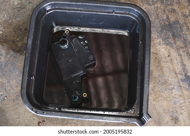 Close-up Of Old Used Automatic Transmission Filter In Oil Drain Pan.