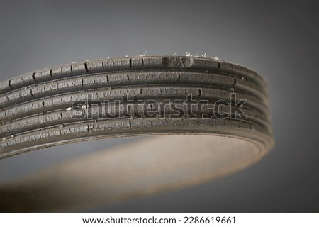 close-up of old used and worn out vehicle drive belt, isolated on gray background, failed and cracked serpentine belt with copy space, replaceable parts