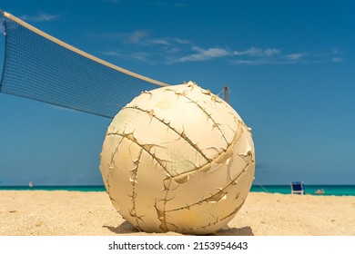 Close-up Of An Old Volleyball On The Background Of A Volleyball Net And The Ocean. Travel And Beach Volleyball Concept. No People.